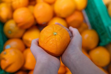Çocuğun eli portakal tutarken, yakın çekim.
