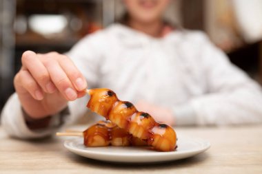 Çocuk Japon mitarashi dango yiyor.