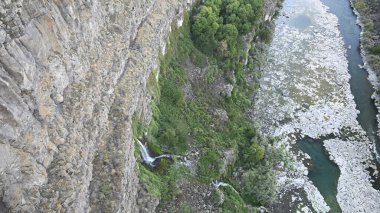 Şelale. Dağlarda şelale. Kayaların arasında şelale. Kayalar ve şelale. Volkanik kayalar. Dik kayalıklar. Kanyonda şelale var. Şelaleli bir kanyon. Volkan Vadisi. Şelaleli volkanik bir kanyon manzarası. Volkanik uçurum. Uçurum.