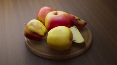 Ahşap bir tahtanın üzerinde duran elma kompozisyonu etrafında döngü çiziyor. Döngü hareketi. Defoktus. Yakın plan..