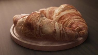 Tahta bir tahtanın üzerinde duran iki kruvasan kompozisyonu etrafında döngü çiziyor. Döngü hareketi. Defoktus. Yakın plan..