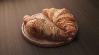 Tahta bir tahtanın üzerinde duran iki kruvasan kompozisyonu etrafında döngü çiziyor. Döngü hareketi. Defoktus. Yakın plan..