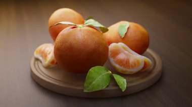 Tahta bir tahtanın üzerinde duran mandalina kompozisyonu etrafında döngü çiziyor. Döngü hareketi. Defoktus. Yakın plan..