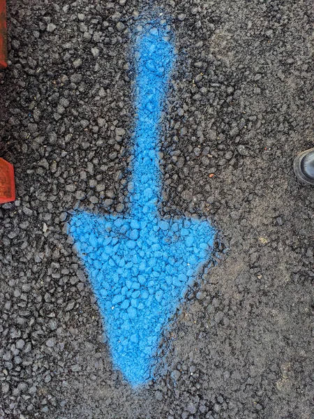 A Blue Arrow Painted on Pavement Pointing