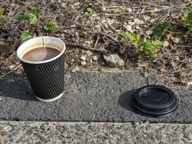 A discarded Coffee Cup and Lid with Liquid Waste Litter on Pavement clipart