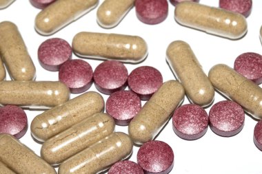 İlaç tedavisi için beyaz zemin üzerinde vitamin kapsülleri ve haplar.