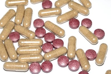 İlaç tedavisi için beyaz zemin üzerinde vitamin kapsülleri ve haplar.