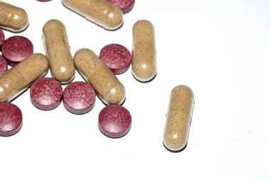 İlaç tedavisi için beyaz zemin üzerinde vitamin kapsülleri ve haplar.