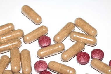 İlaç tedavisi için beyaz zemin üzerinde vitamin kapsülleri ve haplar.