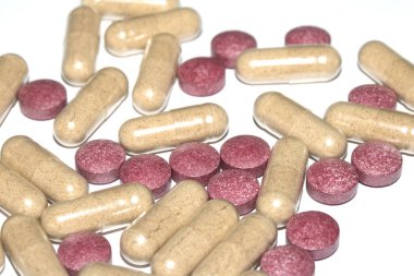 İlaç tedavisi için beyaz zemin üzerinde vitamin kapsülleri ve haplar.