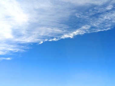 Mavi gökyüzünde ince çizgileri olan büyük beyaz kabarık bulutlar.