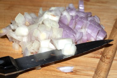 Tahta üzerinde bıçakla doğranmış soğan.
