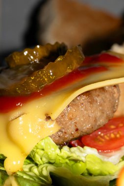 Close up of a Burger in Bun with Cheese and Gherkins and Meta