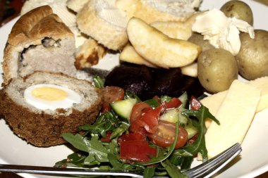 Close Up of a Dinner of Ploughmans Picnic With Pork Pie Scotch Egg Potatoes and Salad clipart