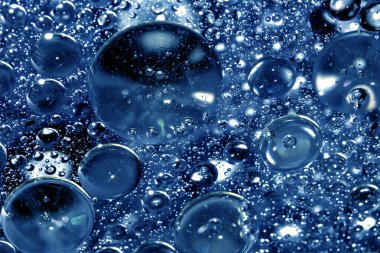 Soyut su çemberindeki yağ baloncuklarını kapatın. Mavi arka planda sıvı ıslak yağmur.