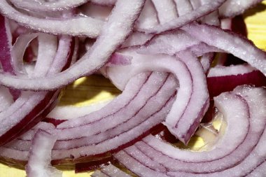 Kesilmiş ve dilimlenmiş kırmızı soğanı ahşap doğrama tahtasına yakın tut.