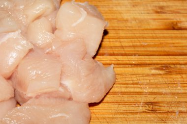 Ahşap kesim tahtasının üzerinde doğranmış çiğ tavuk etini yakın.