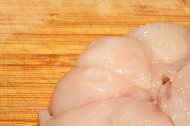 Ahşap kesim tahtasının üzerinde doğranmış çiğ tavuk etini yakın.