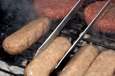Barbekü burgerlerini ve sosisleri çiğ ızgarada pişmeye hazır et.