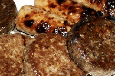 Barbeküye yakın ızgara burger ve sosis tabakta yenmeye hazır et