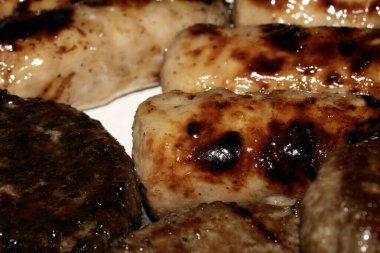 Barbeküye yakın ızgara burger ve sosis tabakta yenmeye hazır et