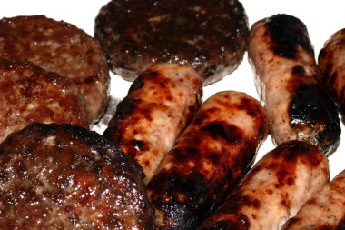 Barbeküye yakın ızgara burger ve sosis tabakta yenmeye hazır et