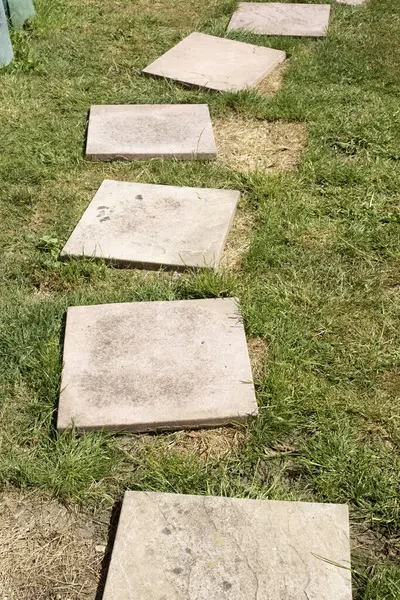 Kırık kaldırım döşemeleri çimlerin üzerinde, bitmesi gerekiyor.