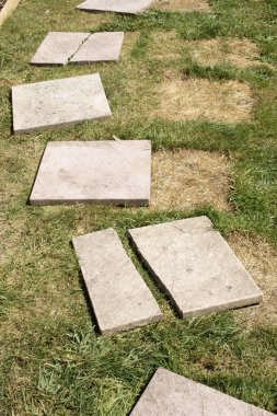 Kırık kaldırım döşemeleri çimlerin üzerinde, bitmesi gerekiyor.