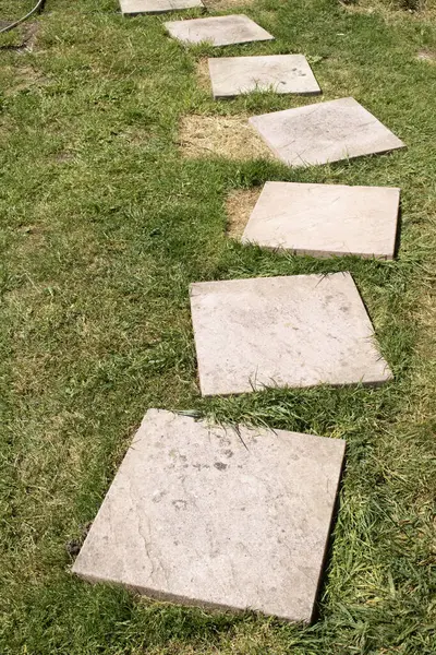 Kırık kaldırım döşemeleri çimlerin üzerinde, bitmesi gerekiyor.