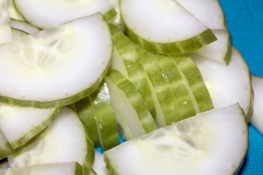 Mavi bir kesme tahtasında doğranmış taze salatalık.