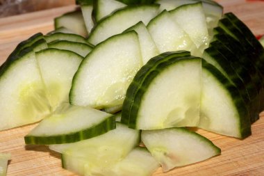 Ahşap doğrama tahtasının üzerinde doğranmış salatalık dilimlerini kapatın.