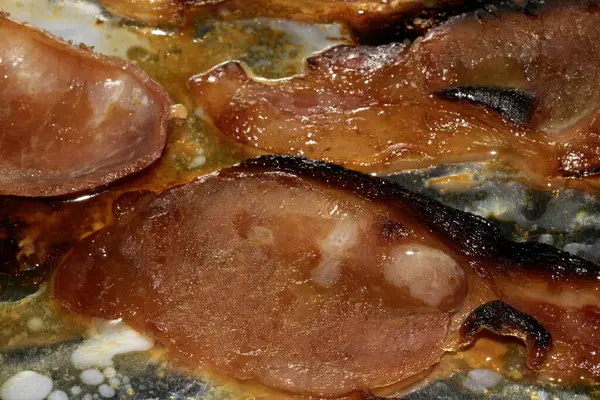 Alüminyum folyoda az pişmiş domuz pastırması şeritlerini yakın.