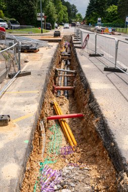 Process of laying of engineering of heating system pipelines in a city street. Heat water pipes in a trench. Color protective nets on buried pipes clipart