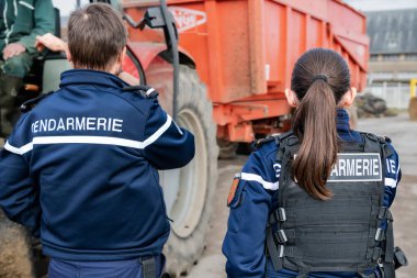 Gendarmes man and woman carrying out a traffic control of a tractor and trailer. France, Normandy, October 2022 clipart