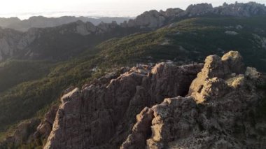 Korsika 'daki Aiguilles de Bavella' nın hava manzarası engebeli granit tepeler, yeşil ormanlar ve kıvrımlı nehirlerden oluşan çarpıcı bir manzara sergiliyor.. 