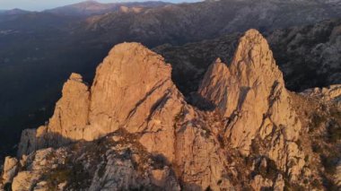 Korsika 'daki Aiguilles de Bavella' nın hava manzarası engebeli granit tepeler, yeşil ormanlar ve kıvrımlı nehirlerden oluşan çarpıcı bir manzara sergiliyor.. 
