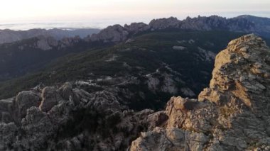 Korsika 'daki Aiguilles de Bavella' nın hava manzarası engebeli granit tepeler, yeşil ormanlar ve kıvrımlı nehirlerden oluşan çarpıcı bir manzara sergiliyor.. 