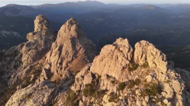 Korsika 'daki Aiguilles de Bavella' nın hava manzarası engebeli granit tepeler, yeşil ormanlar ve kıvrımlı nehirlerden oluşan çarpıcı bir manzara sergiliyor.. 