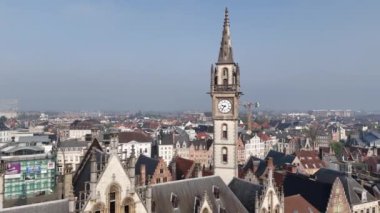 Gent 'in hareketli şehrine tepeden bakan büyük bir saat kulesi etkileyici yüksekliği aşağıdaki resimsel caddelerin üzerine gölge düşürüyor..
