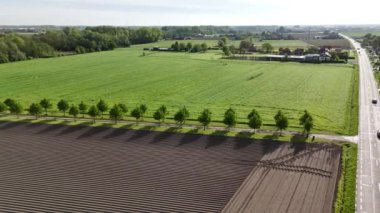 Tarlaları sürülen ve gübrelenen bir çiftliğin havadan bir perspektifini ve arazide uzanan bir yolu deneyimleyin..