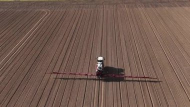 Uçsuz bucaksız bir tarlayı verimli bir şekilde süren ve gübreleyen bir traktörün hava perspektifini izleyin..