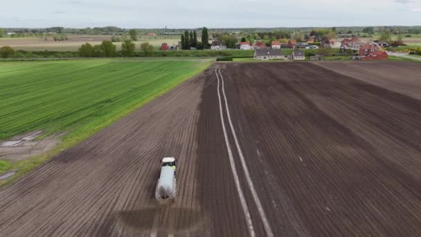 看着拖拉机从鸟瞰的角度为广阔的田野翻耕施肥 免版税图库视频片段