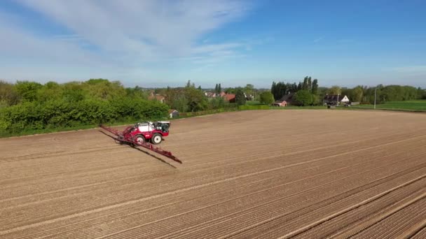 人们看到一辆红色拖拉机犁着一块广阔的土地 为农业目的耕作和施肥 免版税图库视频片段
