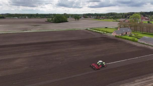 農業目的で土壌を耕作し肥料にするための広大な畑を組織的に耕作するトラクターを目撃する — ストック動画