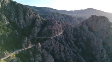 Korsika 'da dolambaçlı bir dağ yolunda süzülen Akdeniz manzarası ve ikonik Calanques de Piana ile engebeli manzaranın nefes kesici güzelliğine tanık olun..