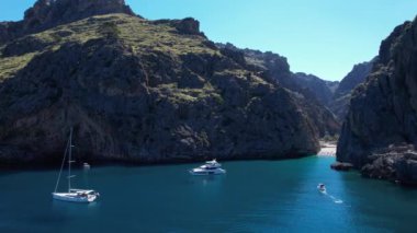 Sa Calobra, Palma de Mallorca 'da Torrent de Pareis' in göz kamaştırıcı arka planıyla bir grup tekne huzur içinde yüzüyor..