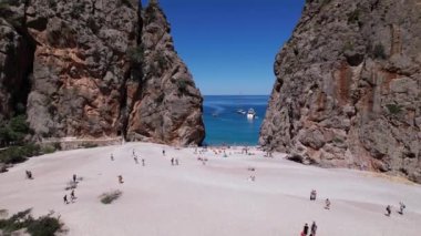 Bir grup insan Sa Calobra, Palma de Mallorca 'da kumlu bir plajda birlikte manzaranın ve güneşin tadını çıkarıyorlar..