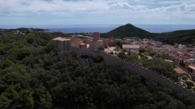 Bir insansız hava aracı Palma de Mallorca adasındaki Capdepera şehrini Palas Sant Salvador 'un görkemli dağlarıyla yakalar..