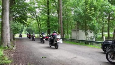 Bir grup motosikletçi sık bir ormanda sarmaşıkla kaplanmış ağaçlarla geziyor..
