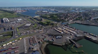 Kalabalık bir kargo limanının havadan görüntüsü, çok sayıda kamyon ve büyük bir gemi kenetlenmiş..